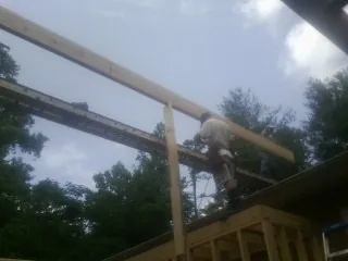 Carpenter setting a ridge beam over a new addition frame — Ice Dam Removal by Roofing Brothers in Corning