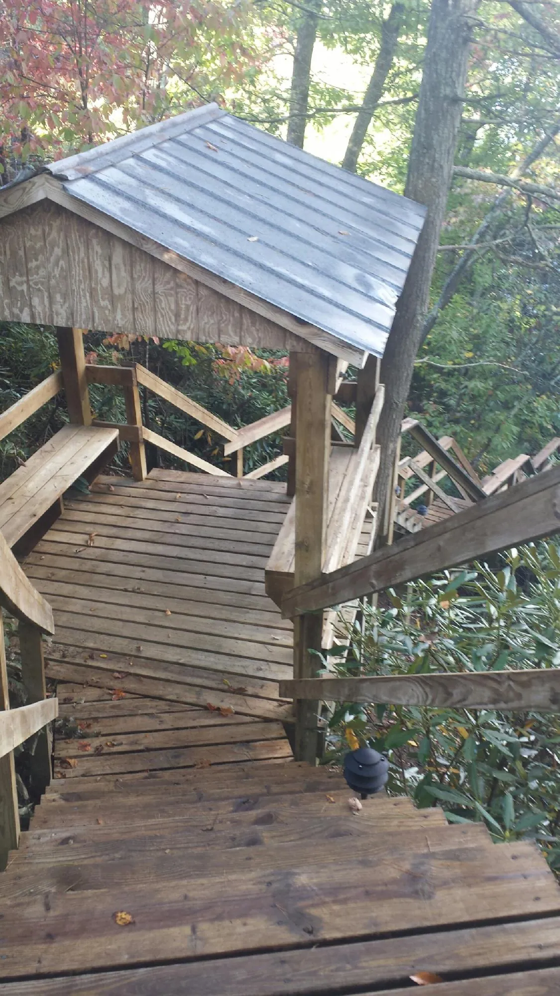 Metal roofed shelter over wooden steps on a wooded walkway — Skylight Repair & Installation work by our crew in Corning